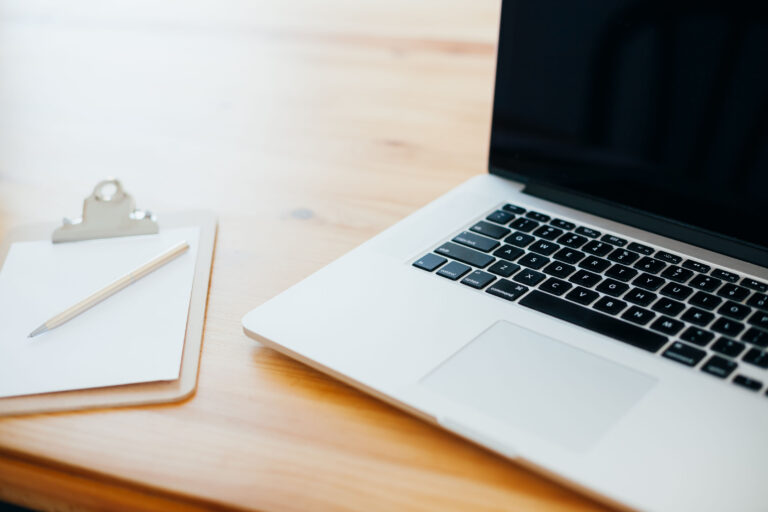 Laptop mit WordPress auf einem Holztisch, daneben Notizblock und Stift